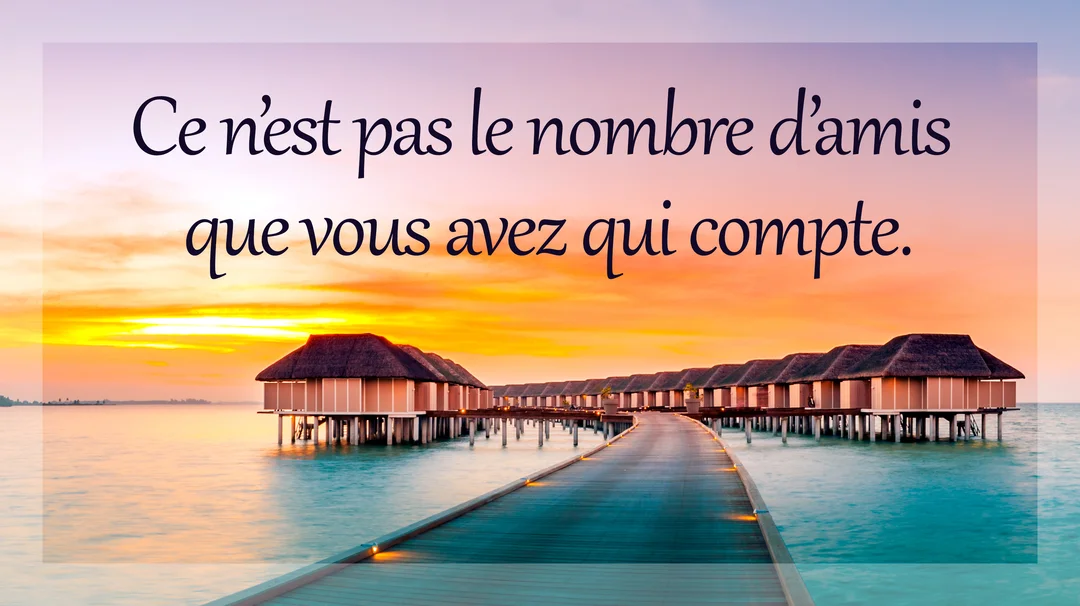 Une rangée de bungalows sur pilotis s'étend sur une mer calme sous un ciel de coucher de soleil vibrant, avec un ponton en bois.