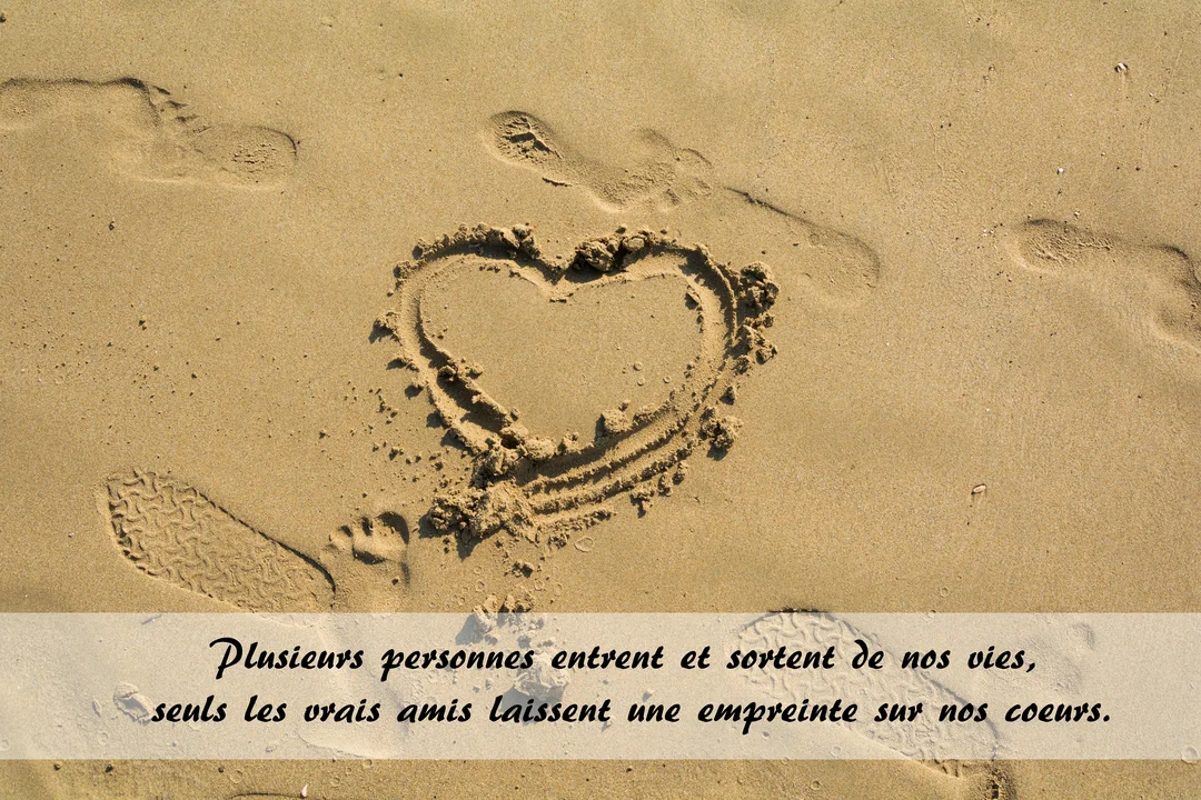 Vue de dessus d'une plage de sable où un cœur est dessiné à côté d'empreintes de pas, sous une lumière chaude et dorée.