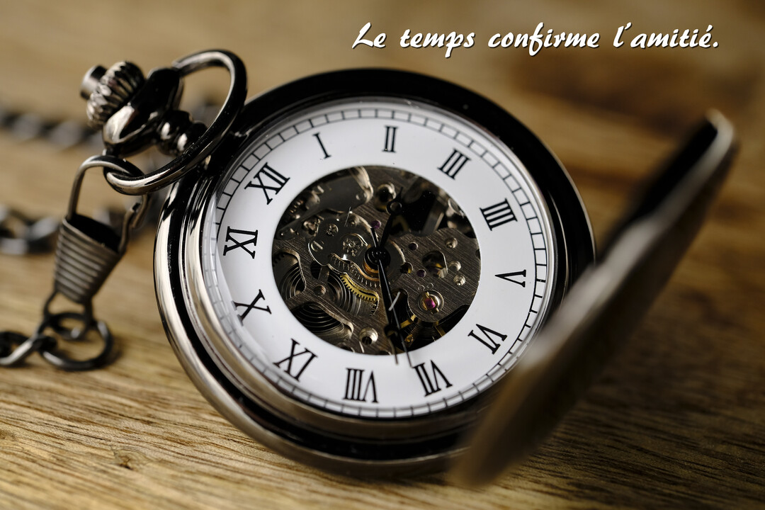 Gros plan sur une montre à gousset argentée ouverte, révélant son mécanisme complexe, posée sur une surface en bois texturé.