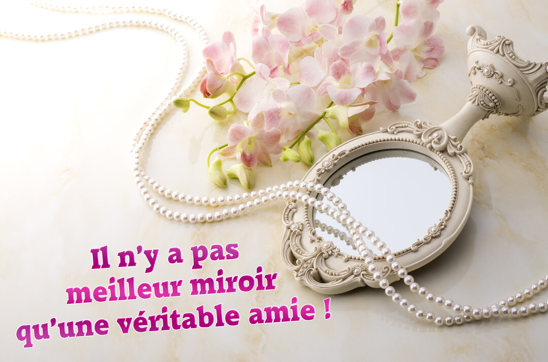 Une composition élégante montre un miroir à main de style ancien, un collier de perles et des fleurs d'orchidées roses sur un fond marbré.
