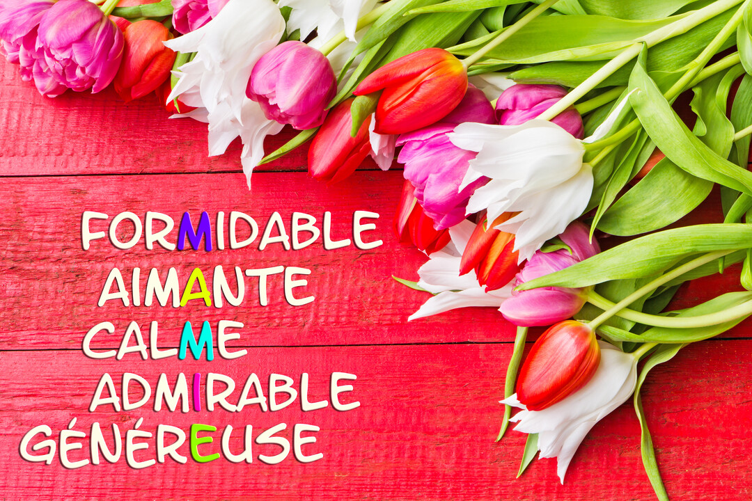 Sur un fond en bois rouge, des tulipes roses, rouges et blanches encadrent un acrostiche de qualités dont les lettres colorées épellent 'Mamie'.