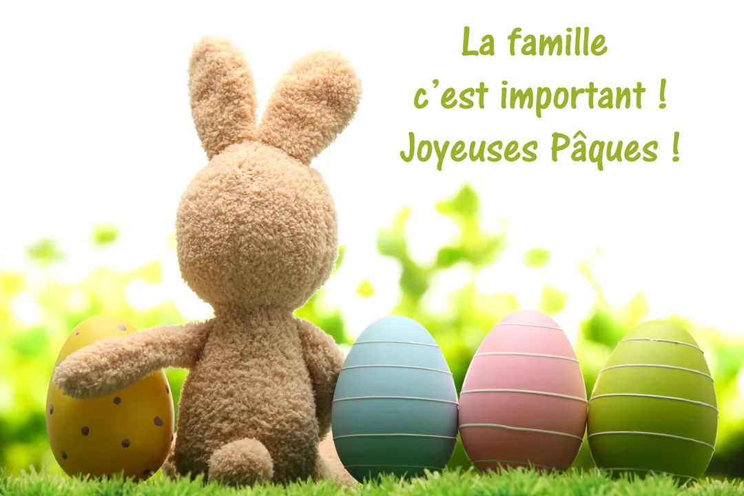 Un lapin en peluche beige est assis de dos dans l'herbe, entouré de quatre œufs de Pâques décorés de couleurs pastel.