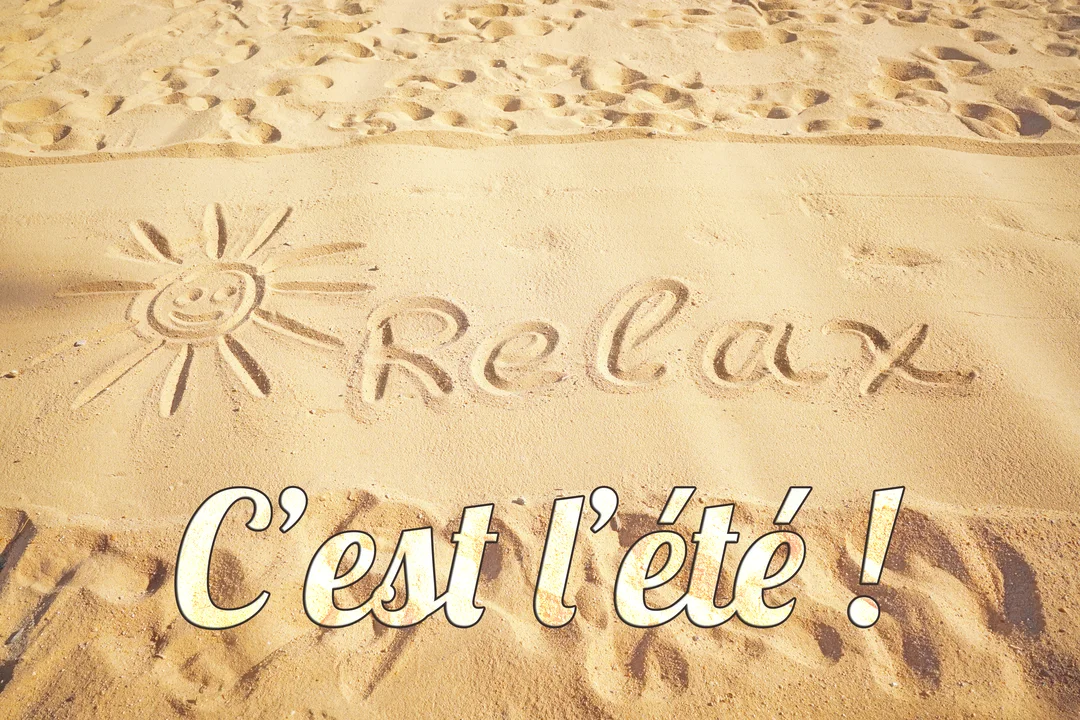 Une photo de plage où le mot 'Relax' et un soleil souriant sont dessinés dans le sable doré, avec quelques empreintes de pas.