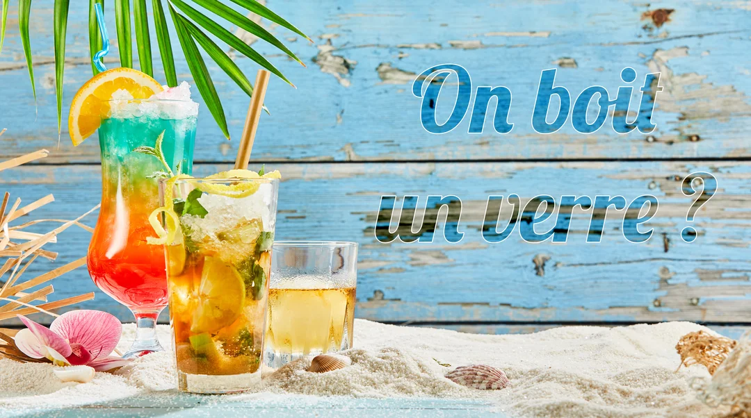 Trois verres de cocktails estivaux sont posés sur du sable devant un fond en bois bleu, avec le texte 'On boit un verre ?'.