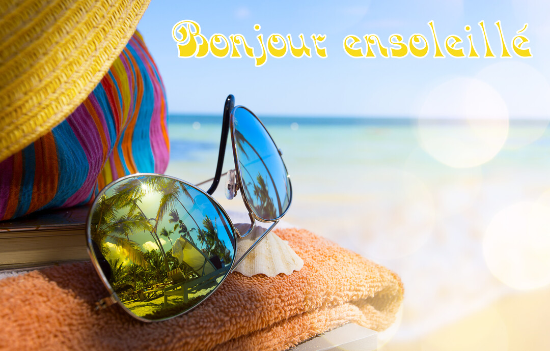 Scène de plage en gros plan avec des lunettes de soleil, un chapeau et une serviette, avec la mer en arrière-plan flou.