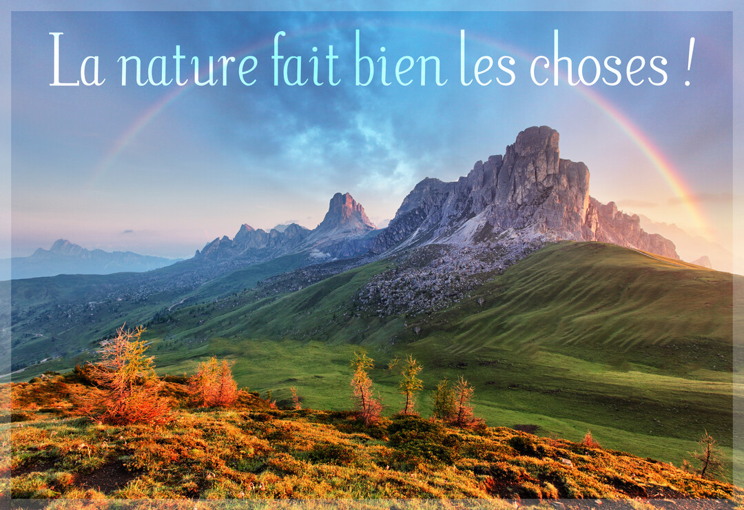Un paysage de montagne spectaculaire sous un ciel nuageux, traversé par un arc-en-ciel, avec des collines verdoyantes et des arbres aux couleurs d'automne.