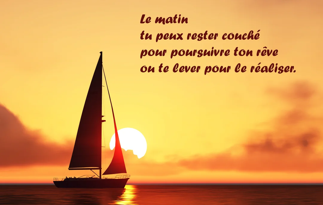 Un voilier en silhouette navigue sur une mer calme au lever du soleil, dont les tons chauds et orangés illuminent le ciel.