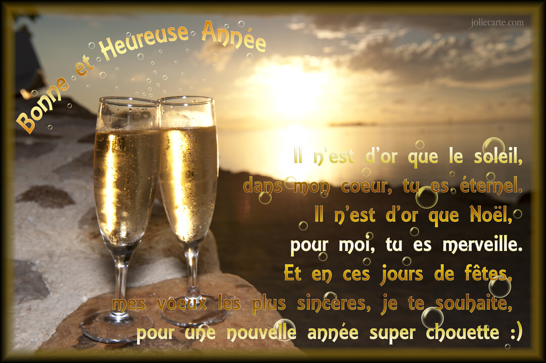 Deux coupes de champagne sont posées sur des rochers au premier plan, avec un coucher de soleil doré sur l'océan en arrière-plan.