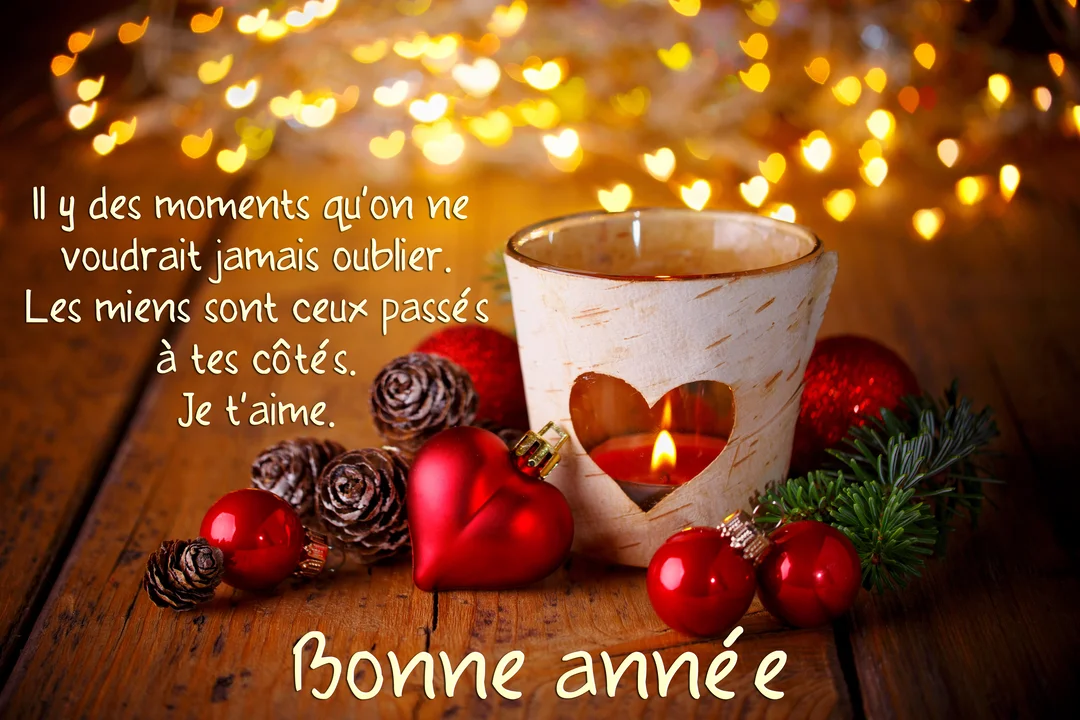 Une composition festive sur une table en bois avec une bougie allumée dans un photophore, des boules de Noël et un cœur rouge.