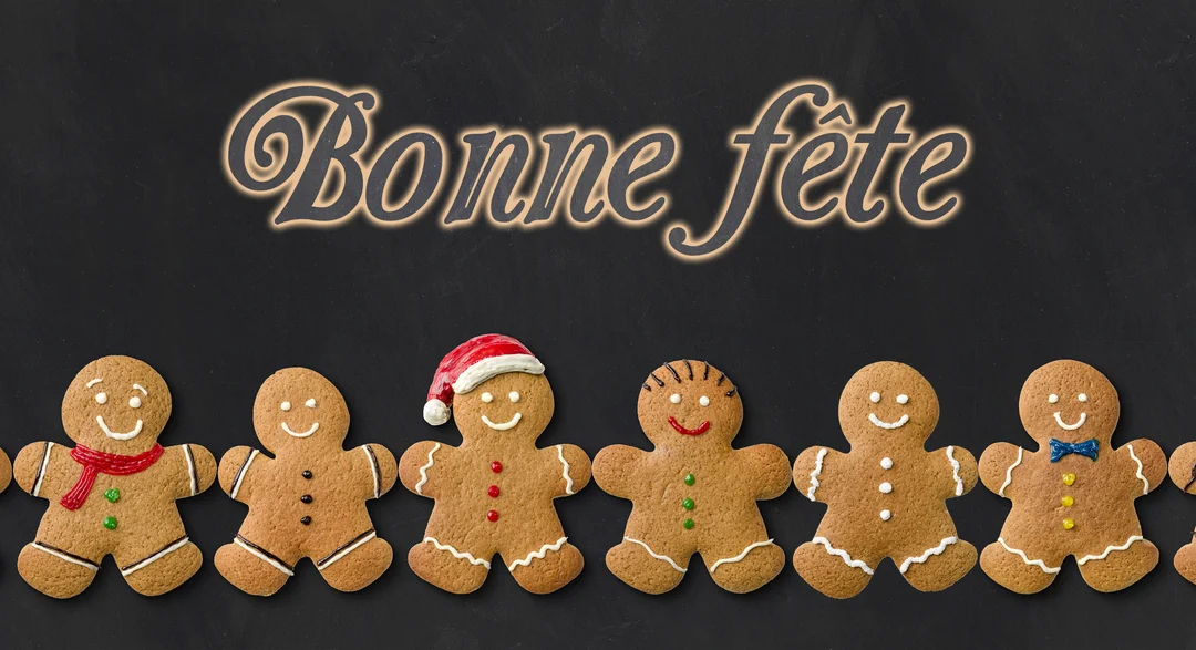 Une rangée de bonshommes souriants en pain d'épices est alignée sous le texte lumineux 'Bonne fête' sur un fond sombre de type ardoise.