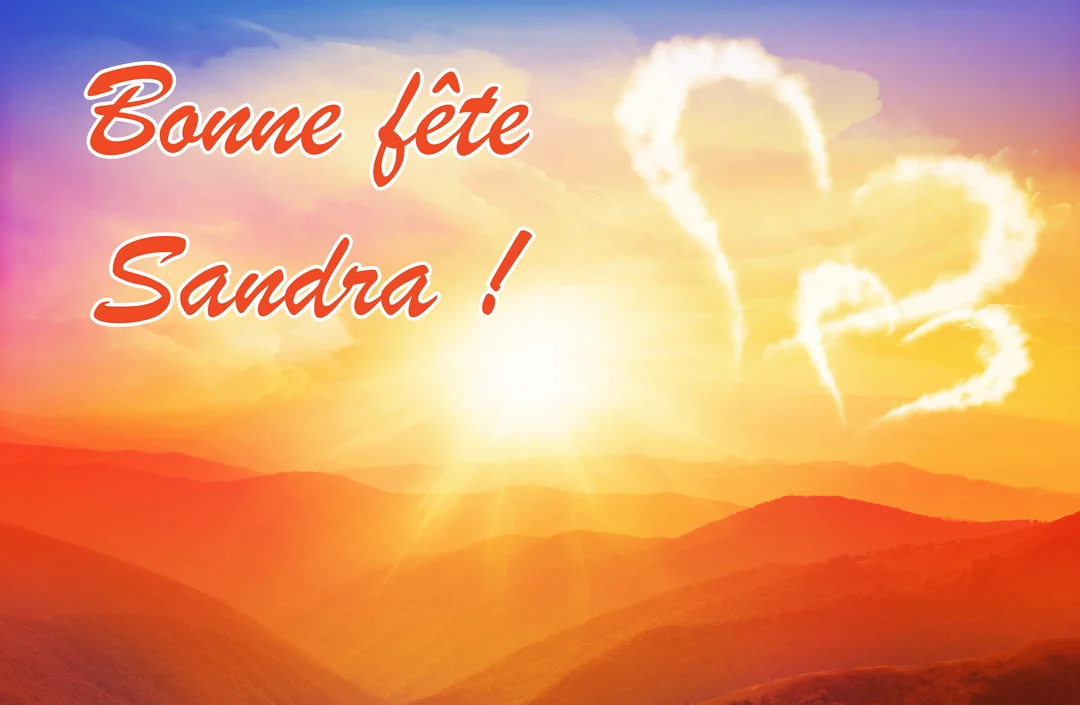 Un paysage montagneux est baigné par un soleil couchant orangé, sous un ciel où flottent deux nuages en forme de cœur et le texte 'Bonne fête Sandra !'.