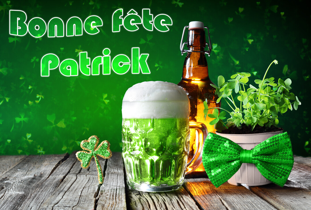 Une chope de bière verte est posée sur une table en bois, à côté de trèfles dans un pot, d'un nœud papillon à paillettes et d'une bouteille.