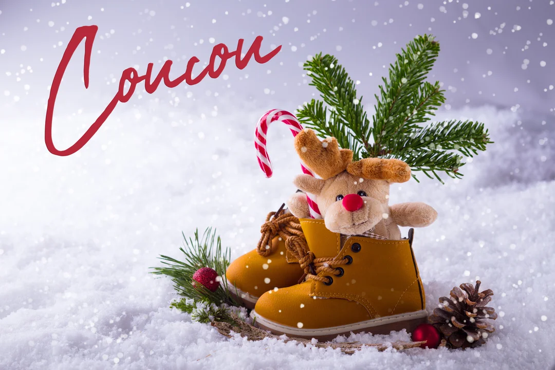 Une paire de bottines jaunes dans la neige contient une peluche de renne, un sucre d'orge et une branche de sapin hivernal.