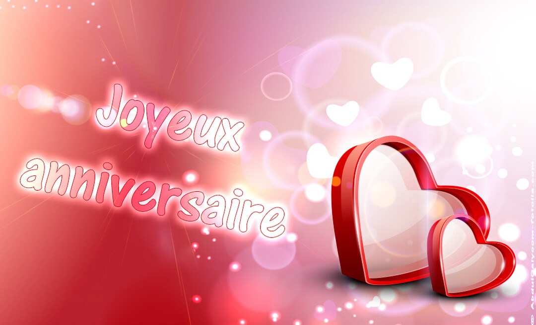 Une carte d'anniversaire romantique montrant deux cœurs rouges en 3D sur un fond lumineux rose et rouge avec le texte 'Joyeux anniversaire'.
