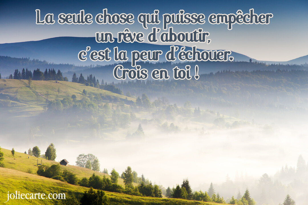 Paysage de montagnes verdoyantes avec des forêts de sapins, une vallée remplie de brume et une citation inspirante sur la confiance en soi.