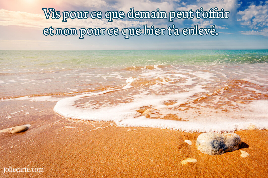 Une vague d'écume blanche se retire du sable doré d'une plage, sous un ciel bleu clair et un soleil éclatant à l'horizon.