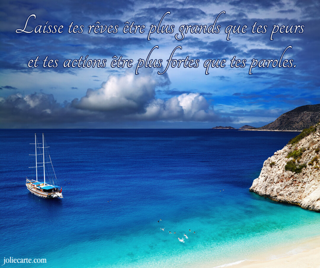 Un voilier est ancré dans une mer d'un bleu profond près d'une crique, sous un ciel nuageux portant une citation motivante.