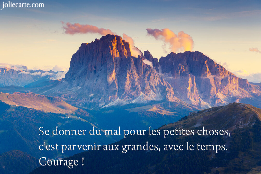 Une chaîne de montagnes aux sommets rocheux et escarpés, illuminés par la lumière dorée du soleil levant sous un ciel clair.