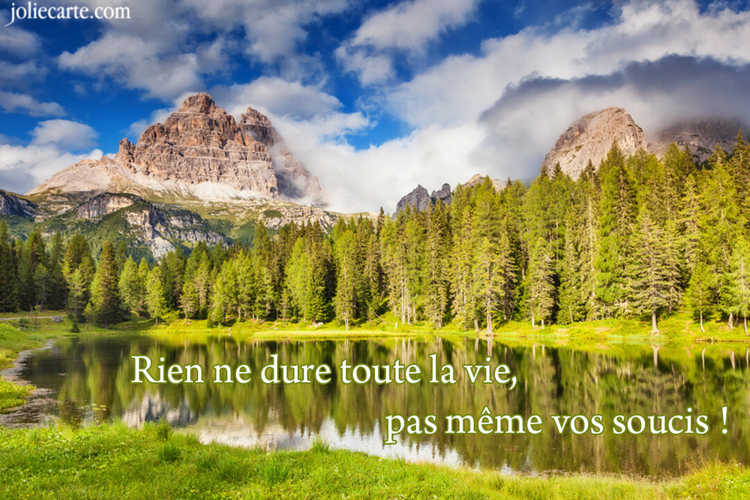 Un majestueux paysage de montagne avec un lac paisible et une forêt de sapins, sous un ciel bleu parsemé de nuages blancs.