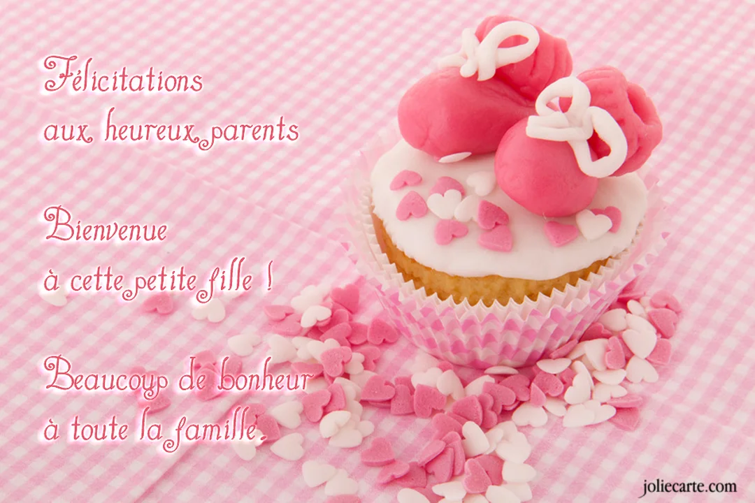 Un cupcake avec un glaçage blanc et des chaussons de bébé roses est posé sur une nappe à carreaux rose et blanche.