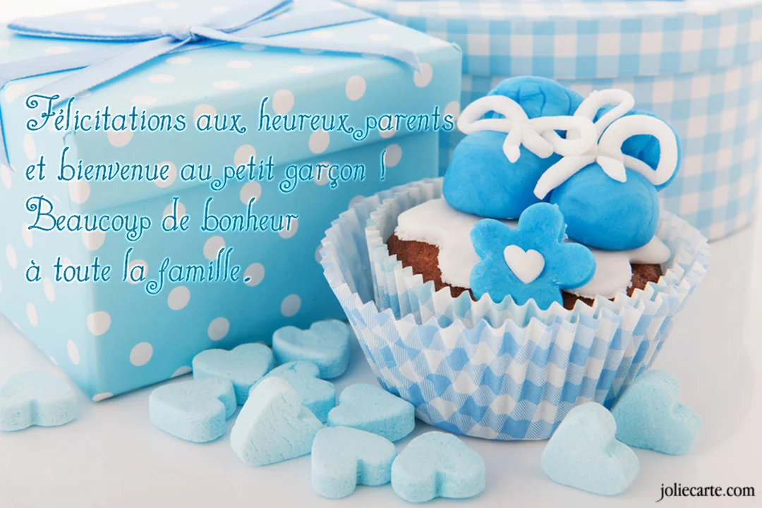 Une mise en scène pour une naissance de garçon avec un cupcake, des chaussons bleus, un cadeau à pois et des cœurs en sucre.