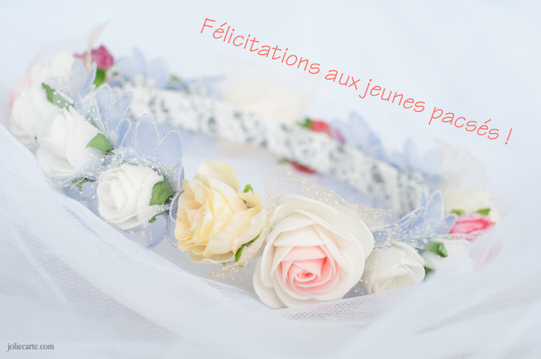 En gros plan, une couronne de fleurs en tissu pastel repose sur un voile blanc, symbolisant une union douce et romantique.
