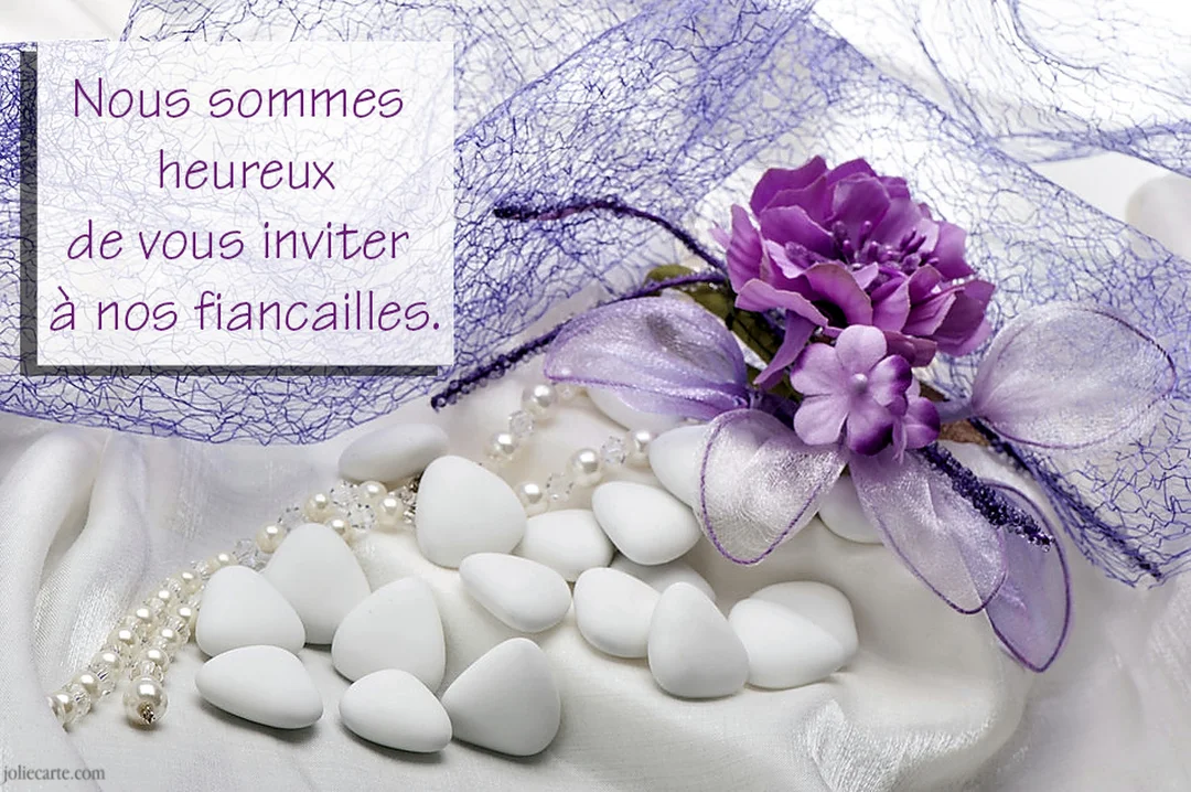Une composition élégante de dragées blanches, de perles et de fleurs artificielles violettes sur un drapé blanc, illustrant une invitation à des fiançailles.