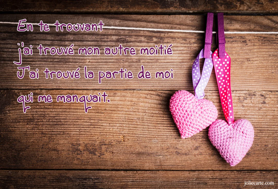 Deux cœurs roses tricotés sont suspendus par des rubans à pois, avec un poème d'amour manuscrit sur un fond de planches de bois.