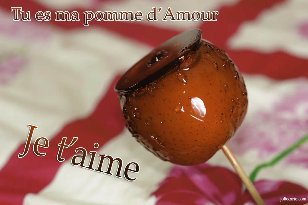 Gros plan sur une pomme d'amour brillante et caramélisée, sur un fond à motifs rouges et blancs, illustrant une déclaration d'amour gourmande.
