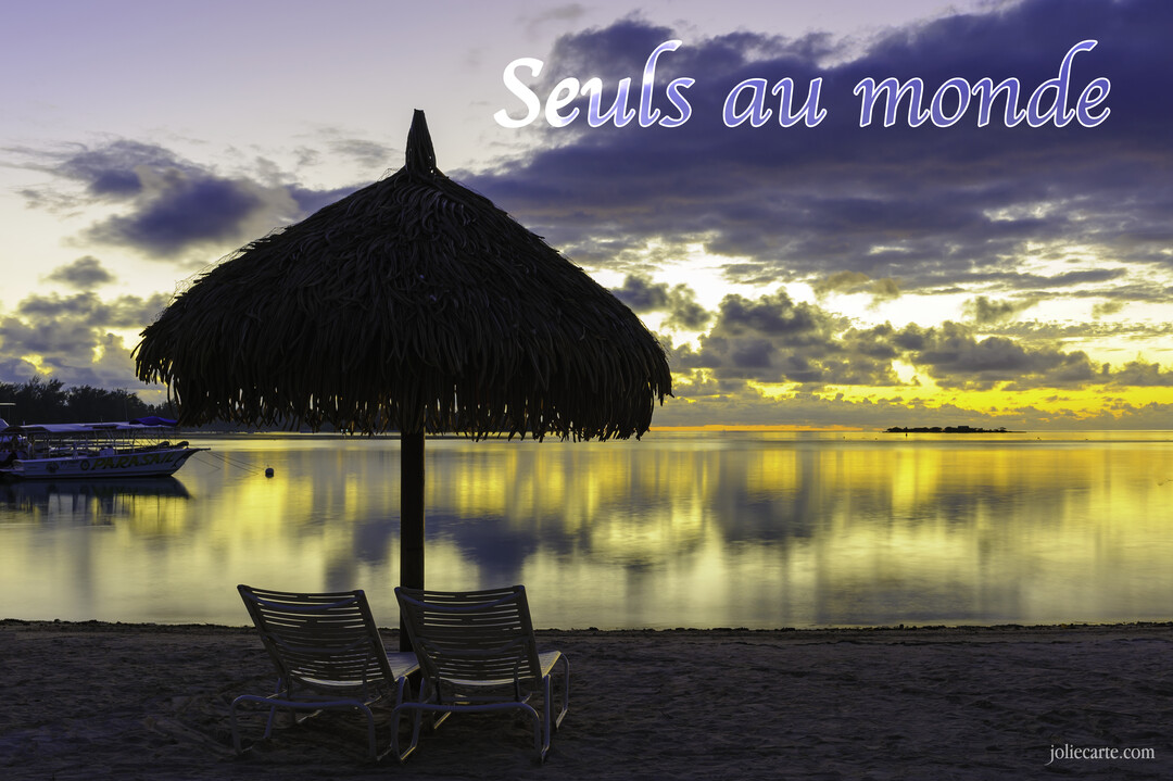 Deux chaises longues sont installées sur une plage de sable, face à une mer calme sous un ciel de crépuscule doré et nuageux.