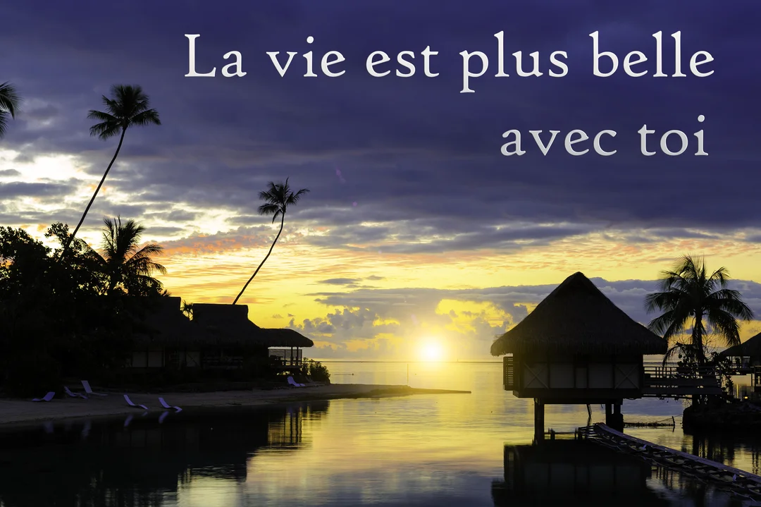 Un paysage paradisiaque au crépuscule, avec des bungalows sur pilotis et des palmiers se reflétant sur une mer calme et dorée.