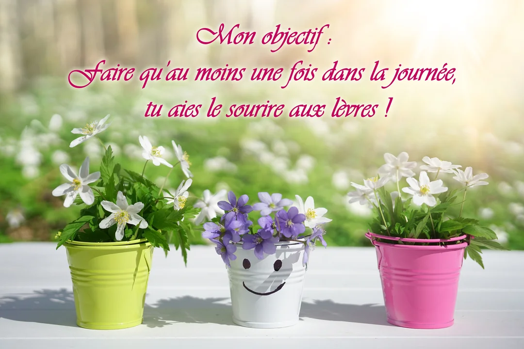 Trois petits seaux colorés remplis de fleurs printanières sont posés sur une table blanche, avec le pot central arborant un visage souriant.