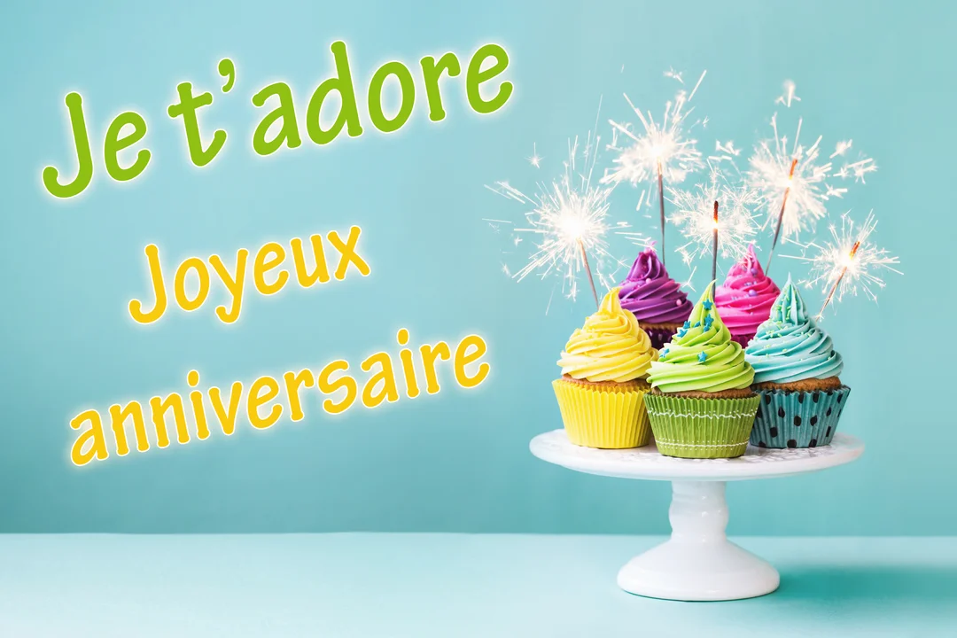 Sur un fond bleu-vert, un présentoir blanc soutient six cupcakes colorés surmontés de glaçage et de cierges magiques allumés.