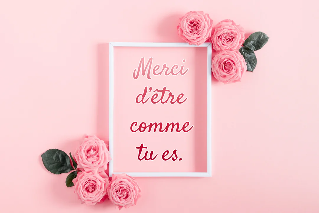 Une composition à plat montre un cadre blanc avec un texte de remerciement, décoré de plusieurs roses roses sur un fond pastel.