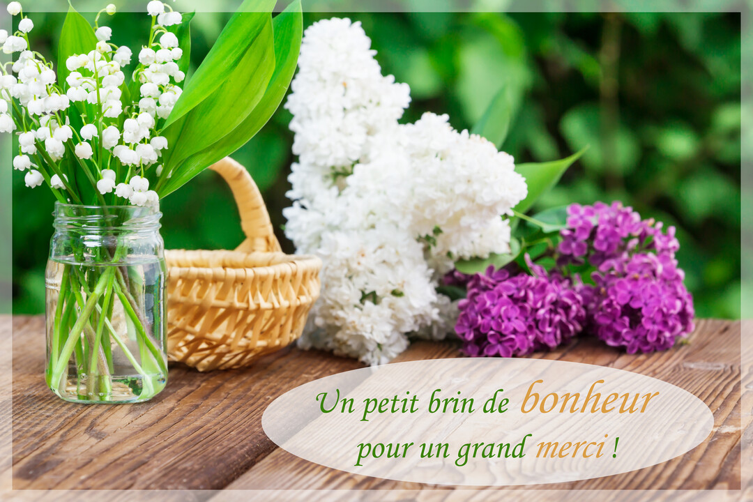 Une composition florale printanière présente un bouquet de muguet et des lilas blancs et violets posés sur une table en bois rustique.