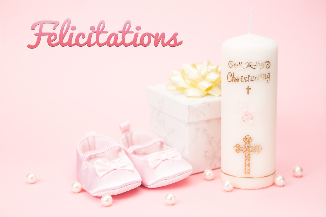 Une composition pour un baptême de fille avec des chaussons de bébé roses, un cierge blanc et un cadeau sur un fond pastel.