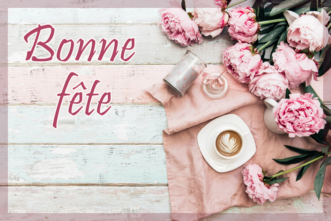 Vue de dessus d'une table en bois avec des pivoines roses, une tasse de café, et le texte 'Bonne fête' écrit en rose.