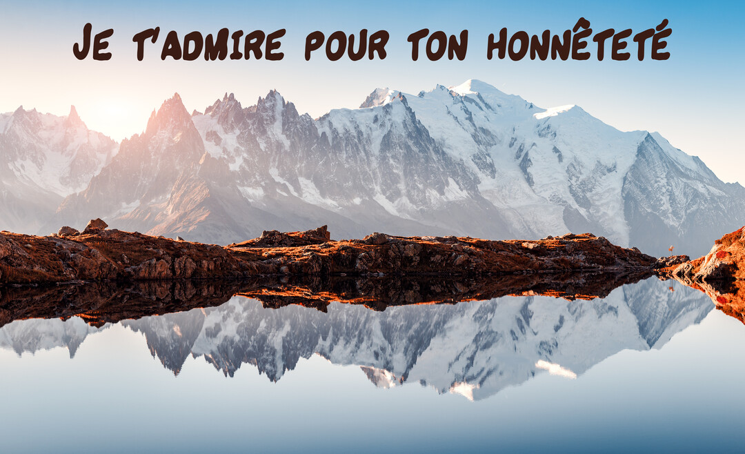 Un majestueux massif montagneux enneigé se reflète parfaitement dans un lac limpide, sous un ciel clair au lever du soleil.