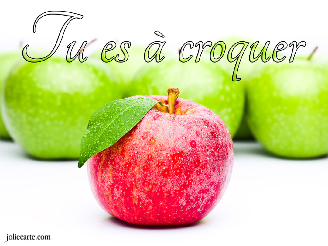 Une pomme rouge brillante avec une feuille verte et des gouttelettes d'eau se trouve devant plusieurs pommes vertes sur un fond blanc uni.