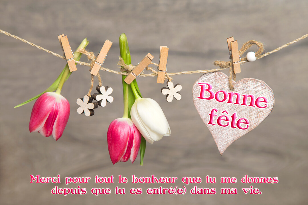 Sur un fond de bois, des tulipes et un cœur en bois sont accrochés à une cordelette à l'aide de petites pinces à linge.