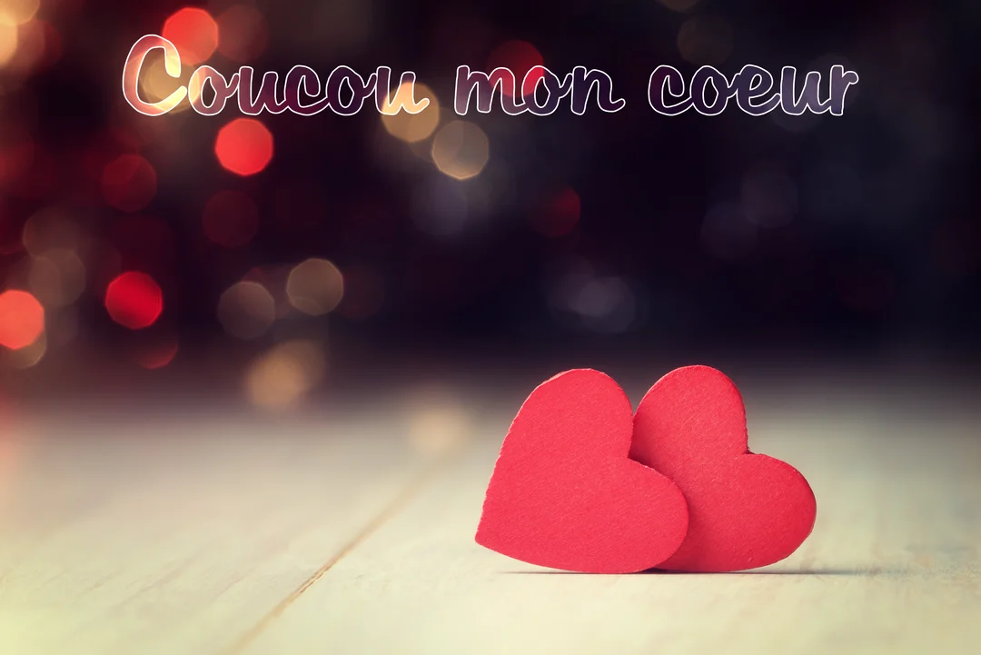 Deux cœurs rouges en papier reposent sur une surface en bois, devant un arrière-plan sombre illuminé par des lumières bokeh rouges et dorées.