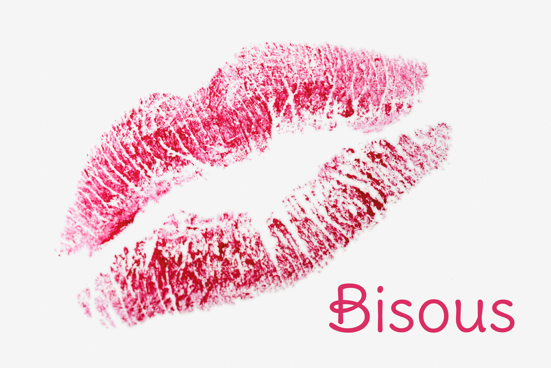 Une empreinte de lèvres rose fuchsia, laissée par un baiser au rouge à lèvres, est visible sur un fond blanc pur.