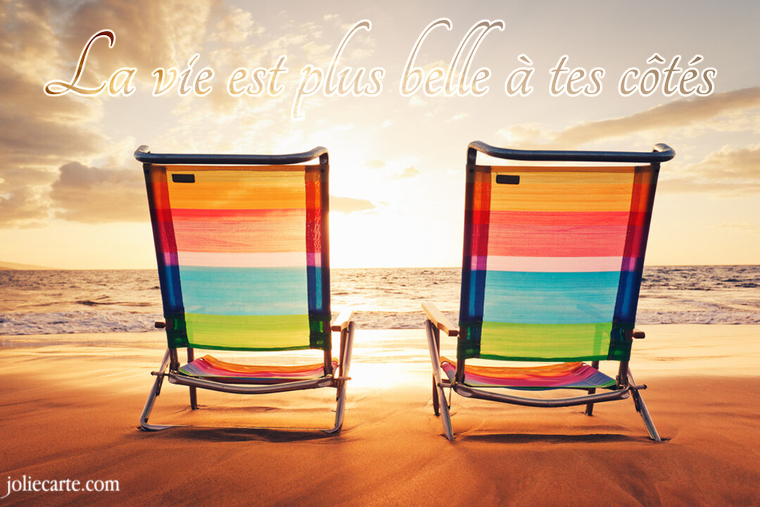 Deux chaises de plage multicolores sont posées sur le sable, tournées vers un coucher de soleil éclatant sur l'océan, illustrant un sentiment de complicité.