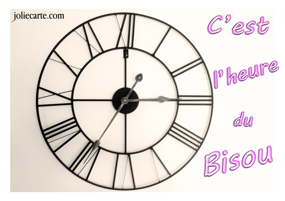 Une horloge murale noire de style vintage sur fond blanc, accompagnée du texte fantaisie rose 'C'est l'heure du bisou'.