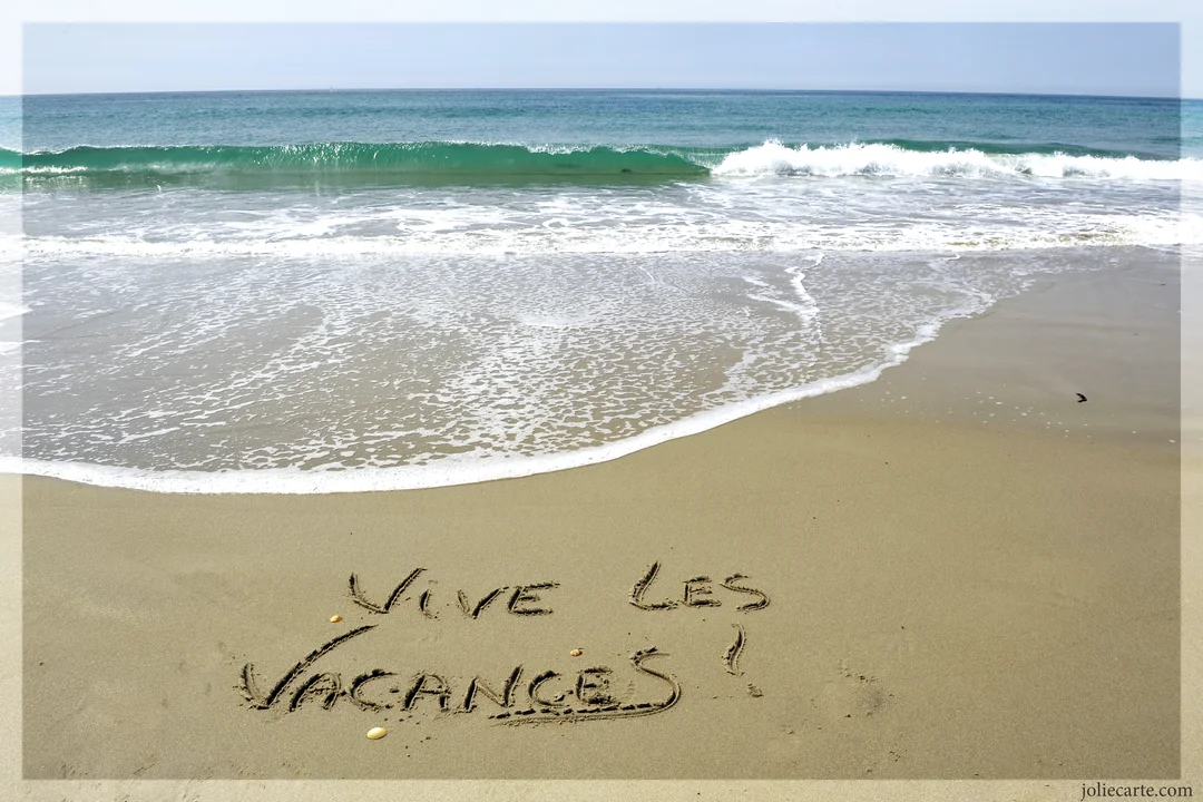 Photographie d'une plage où le message 'Vive les vacances !' est tracé sur le sable, face à une mer calme et un horizon clair.