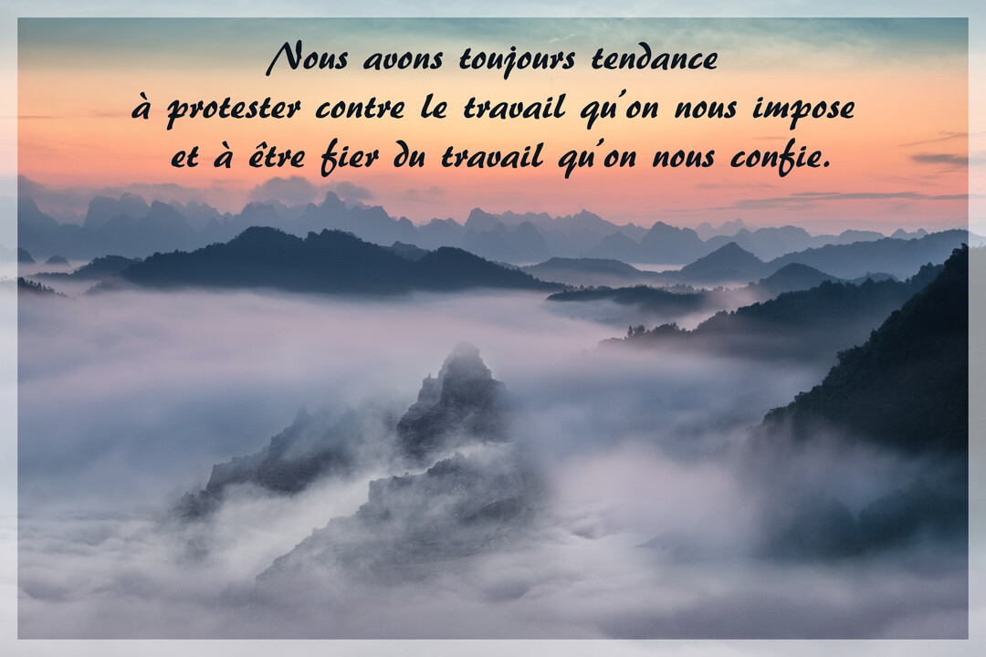 Une citation sur le travail est superposée à une photographie de pics montagneux émergeant d'une mer de nuages au crépuscule.