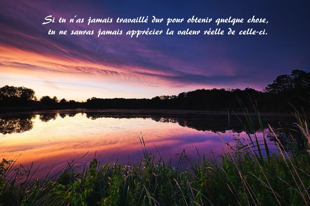 Un paysage de lac au crépuscule avec un ciel aux couleurs vives, violettes et oranges, se reflétant sur l'eau calme, avec une citation superposée.