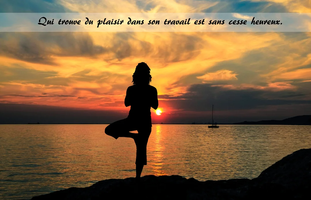 En silhouette, une femme pratique la posture de l'arbre au yoga sur un rocher, face à la mer sous un ciel de crépuscule orangé.