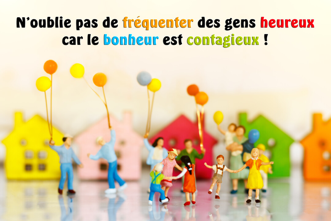 Une scène miniature représente des personnages souriants avec des ballons devant un alignement de petites maisons de toutes les couleurs, illustrant la joie.