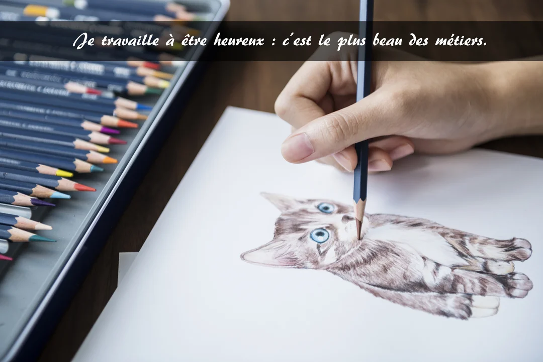 Une main tient un crayon et dessine un chaton réaliste aux yeux bleus sur une feuille, à côté d'une boîte de crayons de couleur.